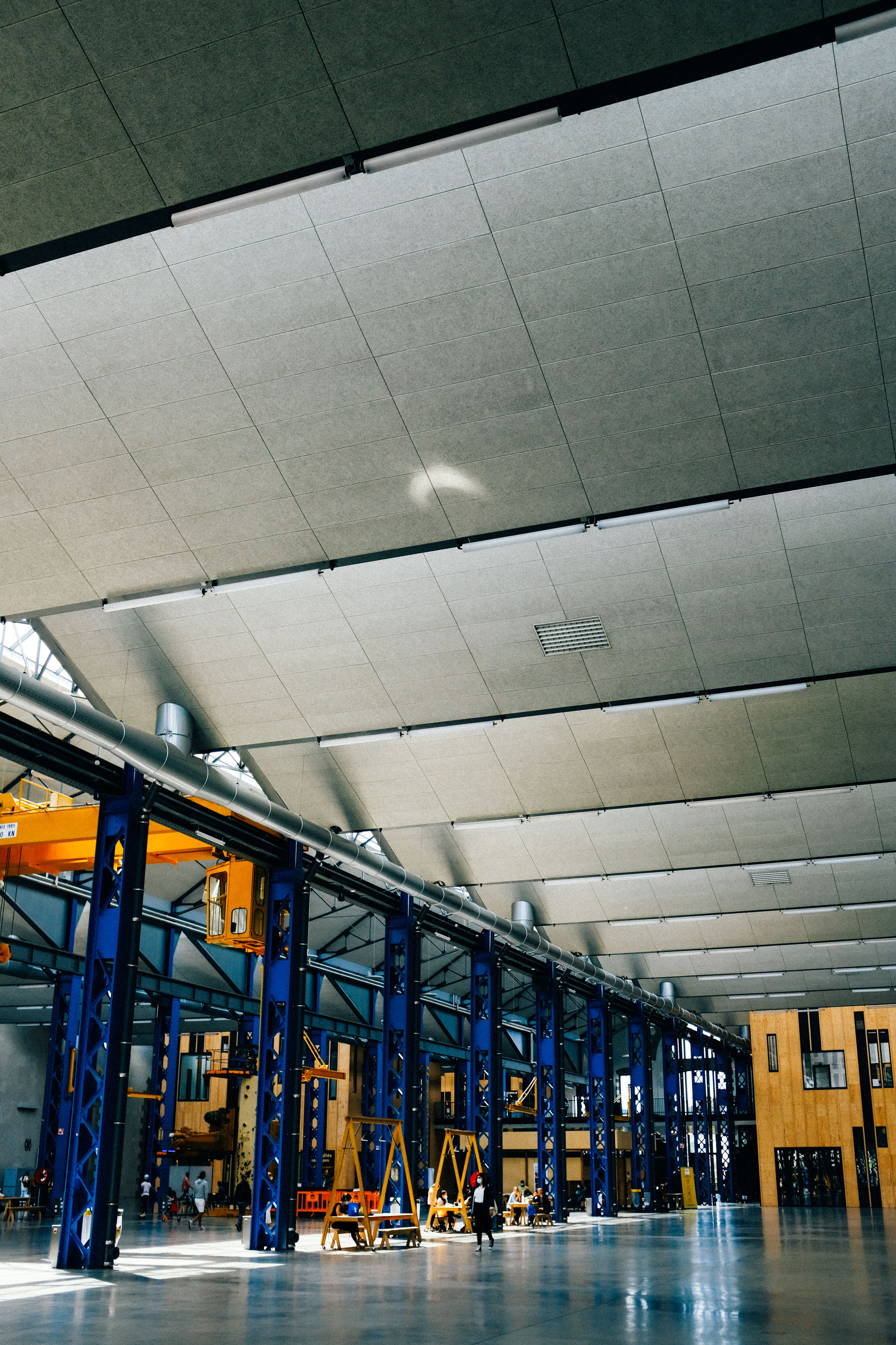 Interior de planta industrial com estrutura metálica e ponte rolante.